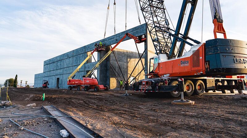 Construction site of NuWu's two-story expansion with a tower crane at golden hour