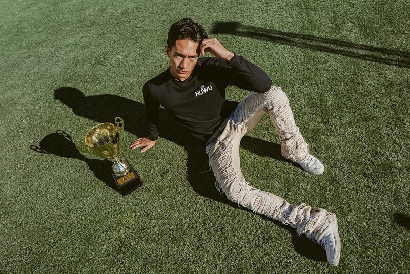 A NuWu Cup champion sitting on grass beside the trophy