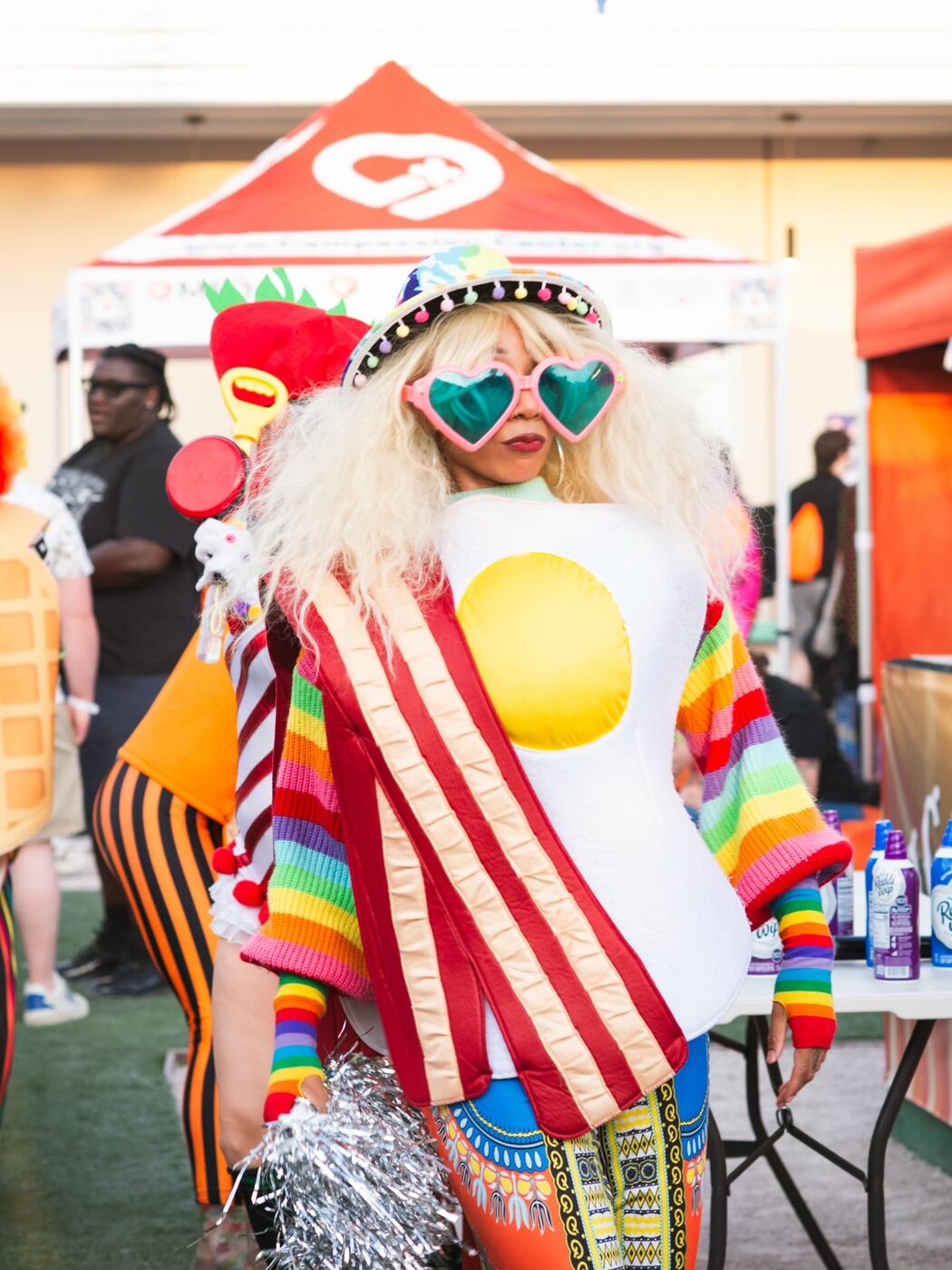 A clown in candy stripes and heart shades among balloons