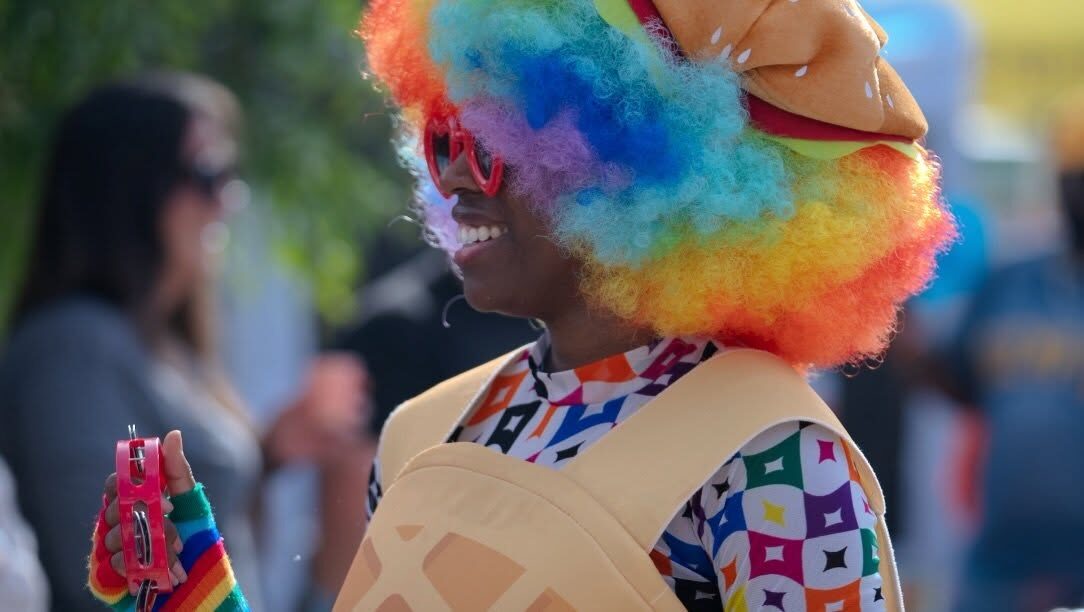 A guest in a rainbow wig and full festival color