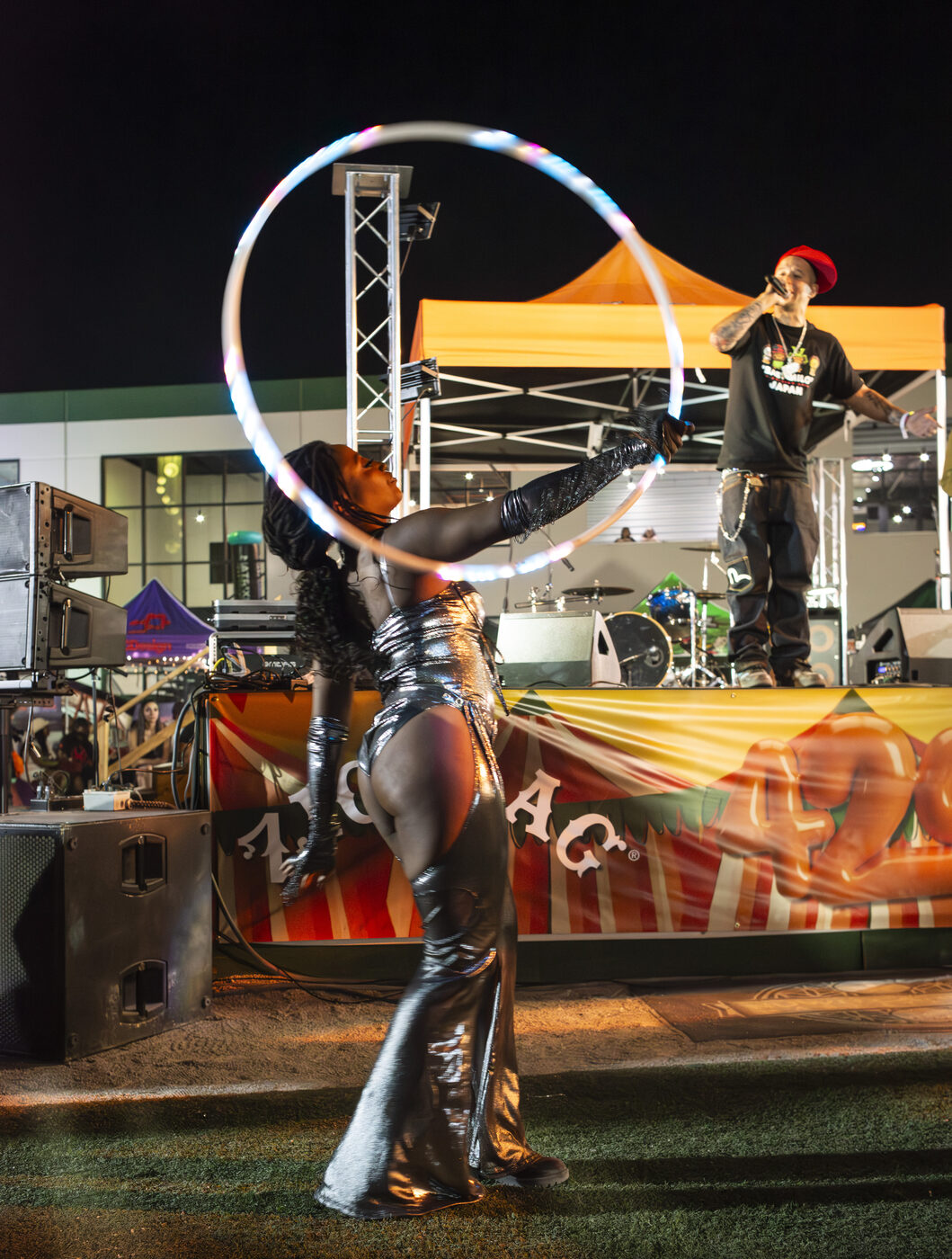 An LED-hoop dancer performs in front of the main stage after dark